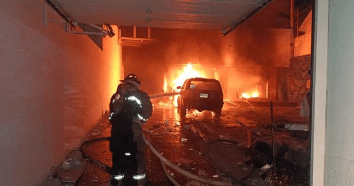 Bombero combatiendo incendio en taller con vehículo en llamas en Mazatlán