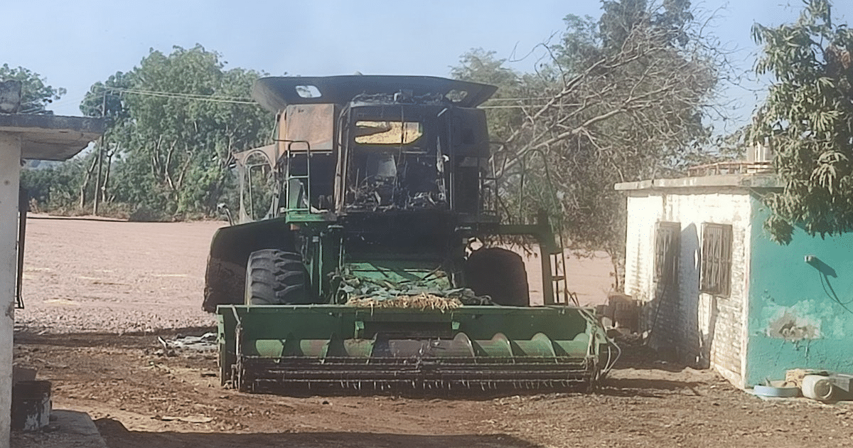 Cosechadora dañada por incendio en Ahome, Sinaloa, cerca de una casa y árboles.