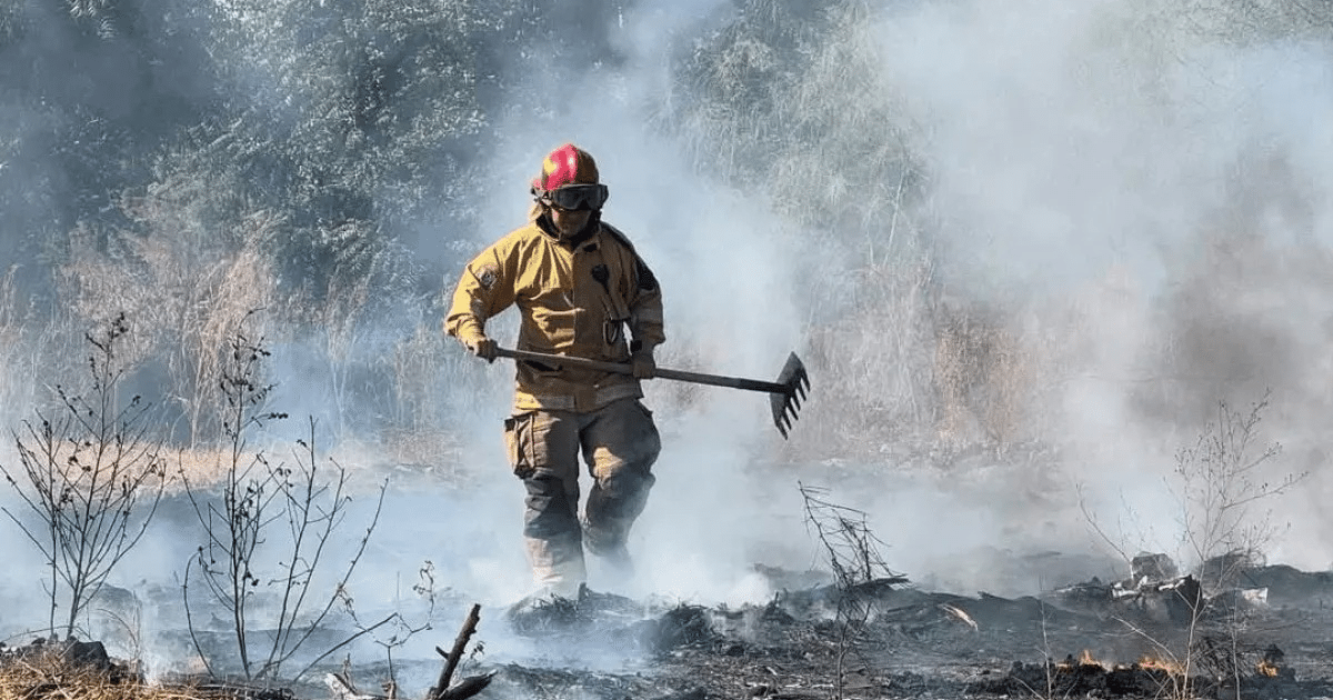 Bombero combatiendo un incendio en Guamúchil, rodeado de humo y llamas.
