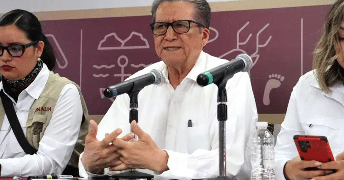 Tres personas en una conferencia sobre manipulación de información en Culiacán, con micrófonos y una botella de agua en la mesa.