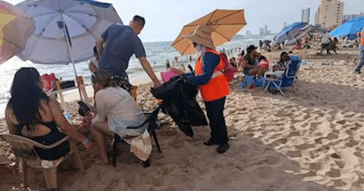 Playa de Mazatlán con operativo de limpieza, sombrillas y personas disfrutando del día.