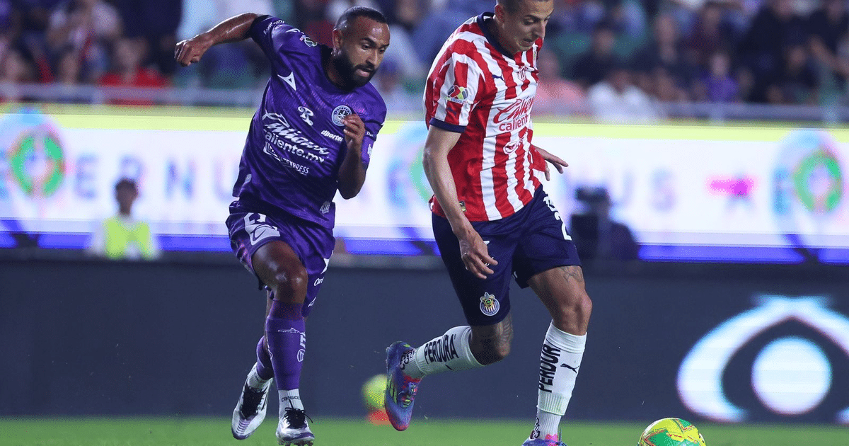 Dos jugadores de fútbol compiten por el balón en un estadio lleno durante el partido Mazatlán vs Chivas.