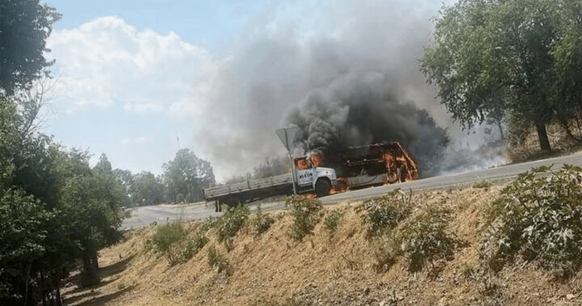 Camión incendiado en carretera rural, vinculado a narcobloqueos en Michoacán tras captura de 'El Doble R'.