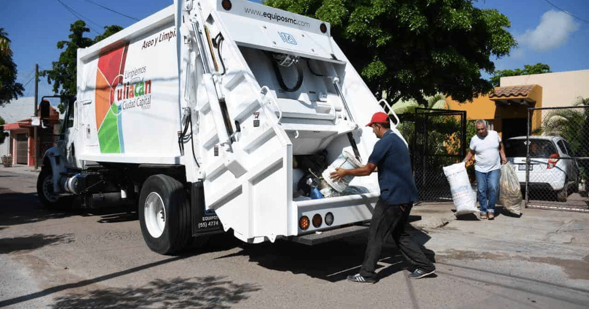 Camión de basura en una calle con trabajadores descargando bolsas de residuos, en un entorno urbano.