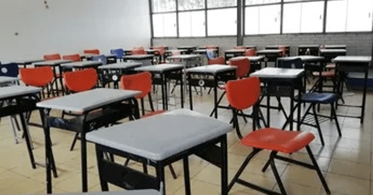 Aula vacía con escritorios grises y sillas de colores en Sinaloa, parte de la campaña de protección educativa.