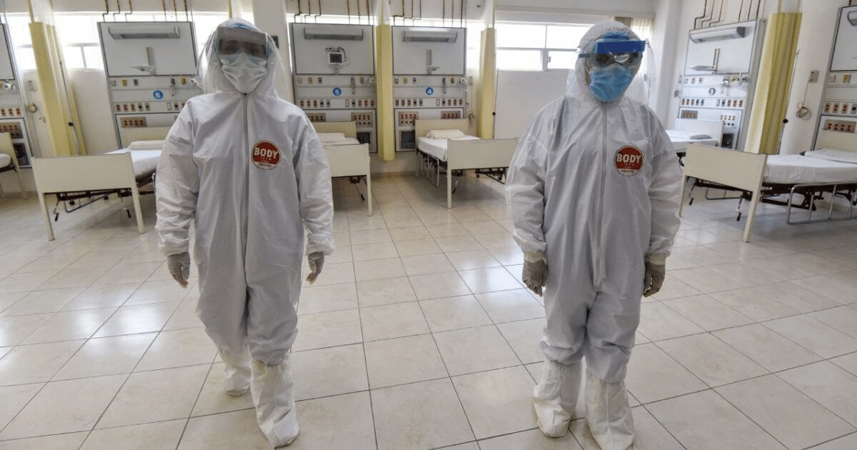 Dos profesionales de la salud con trajes de protección en un hospital durante una emergencia sanitaria.