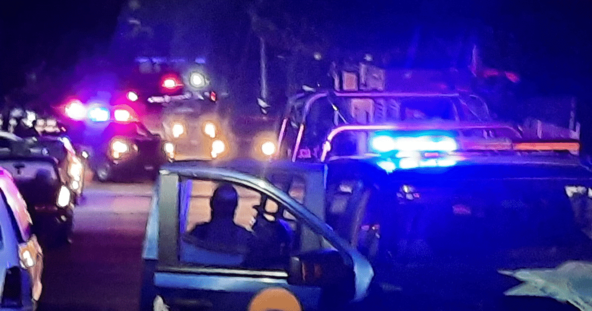 Vehículos con luces parpadeantes en una calle de Culiacán durante un operativo nocturno.