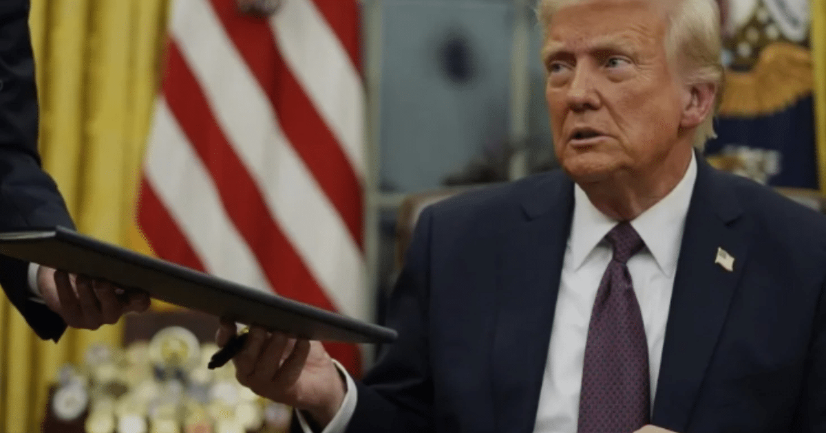 Persona revisando documentos en una oficina con bandera estadounidense de fondo.