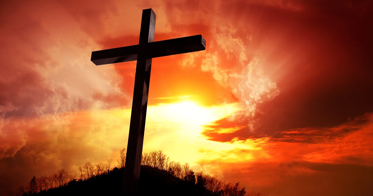 Cruz oscura frente a un cielo dramático al atardecer, simbolizando la espiritualidad de la Semana Santa.