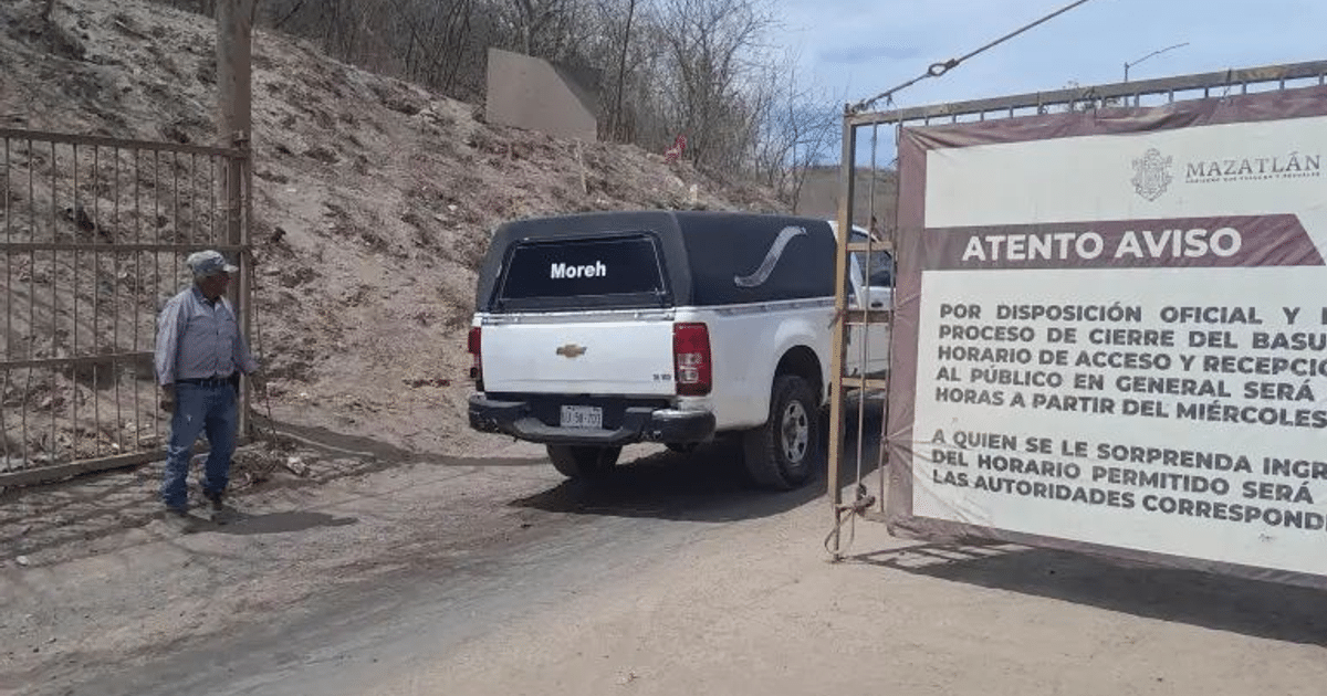 Camioneta blanca estacionada cerca de un portón con un cartel de cierre de basurero en área rural.