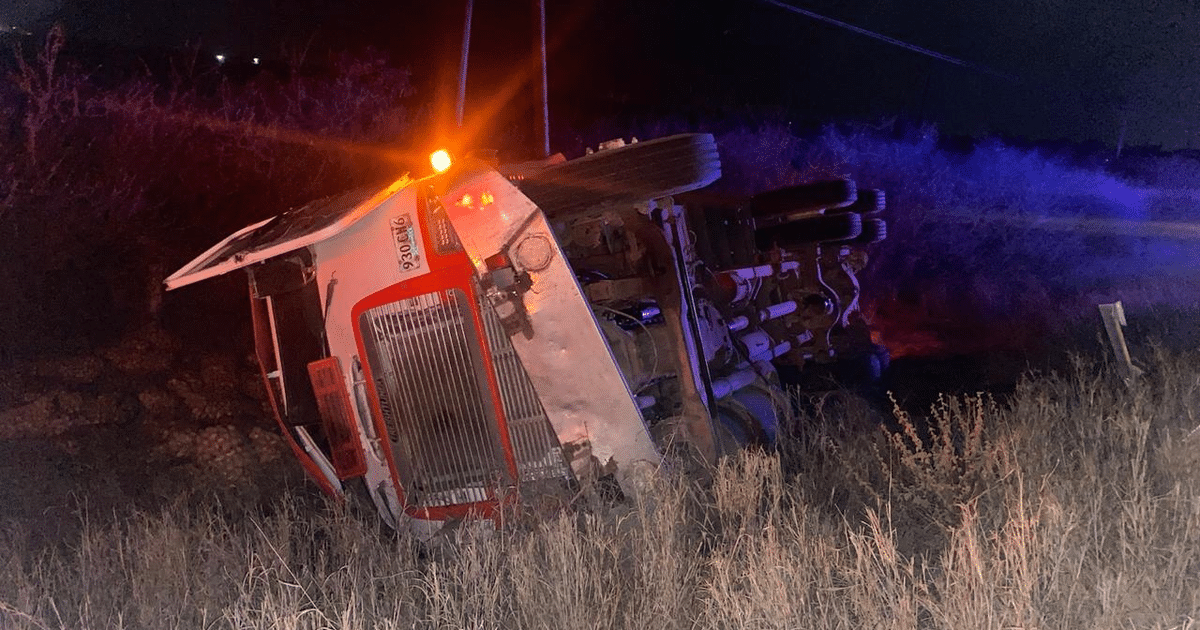 Camión volcado en campo de noche con luces de emergencia