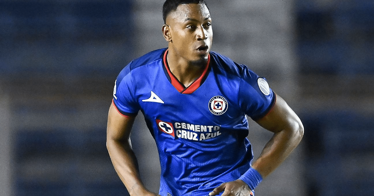Jugador de fútbol de Cruz Azul en uniforme azul y rojo durante un partido en el estadio.