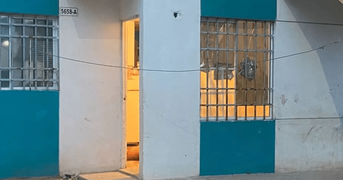 Pared blanca con detalles azules, puerta abierta y ventana con rejas en Culiacán, zona de alta incidencia delictiva.