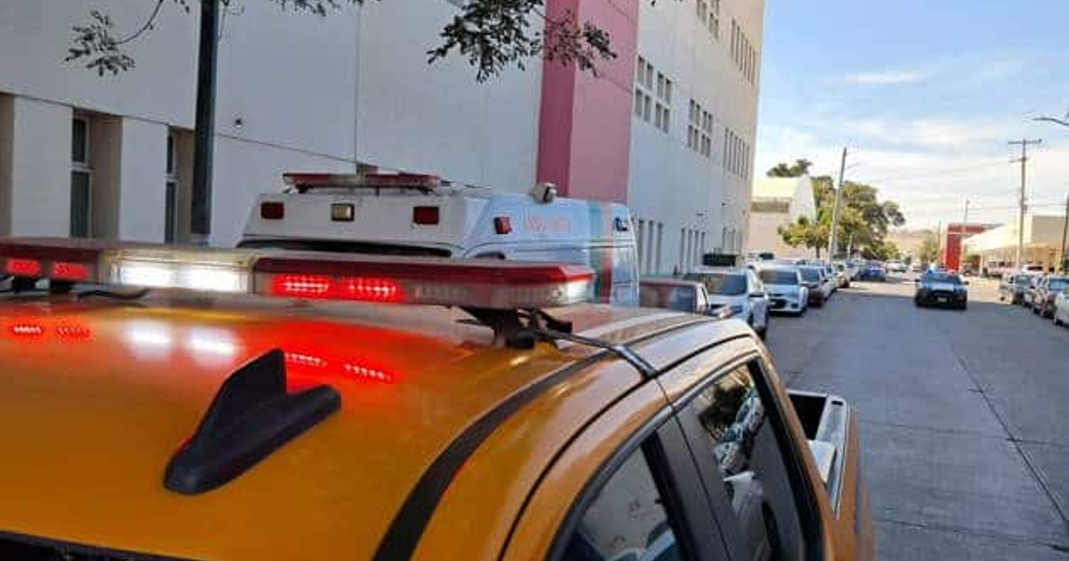 Taxi amarillo con luces de emergencia y ambulancia en escena de accidente en Sanalona
