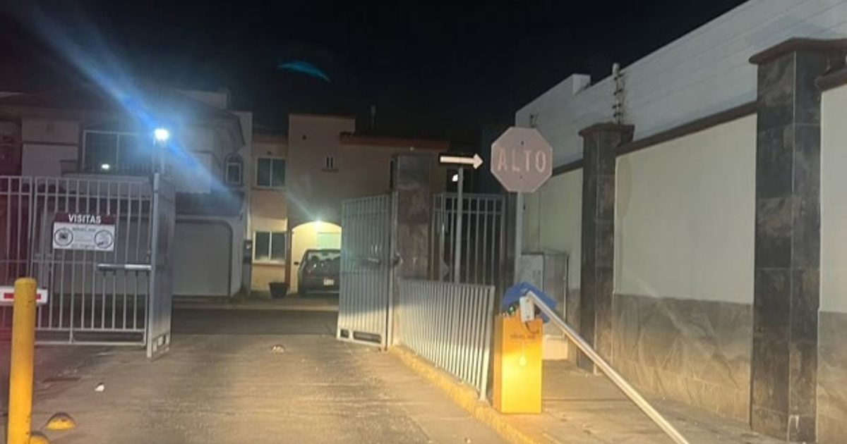 Entrada nocturna a privada Santa Aynes con letrero de 'ALTO' y reja abierta tras asalto