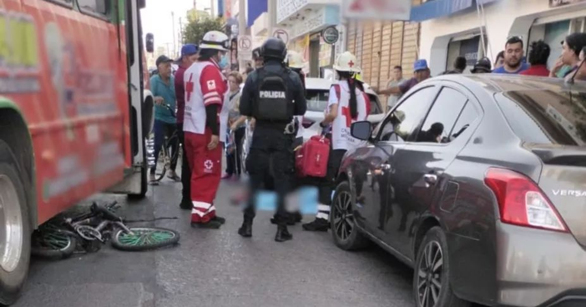 Escena de accidente en Mazatlán con autobús, automóvil y bicicleta en el suelo, rodeados de personal de emergencia y espectadores.