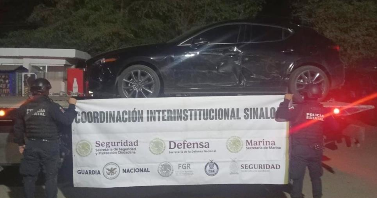 Vehículo negro dañado en camión, rodeado de policías con pancarta de coordinación en Culiacán.