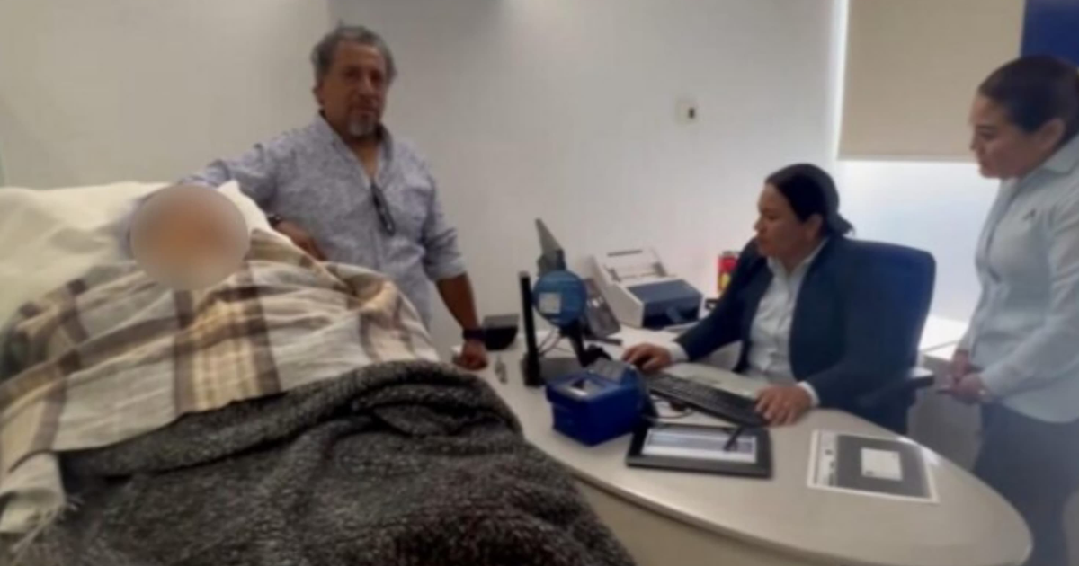 Hombre atendiendo a persona en cama junto a mujeres en oficina, relacionado con actualización biométrica en BBVA.