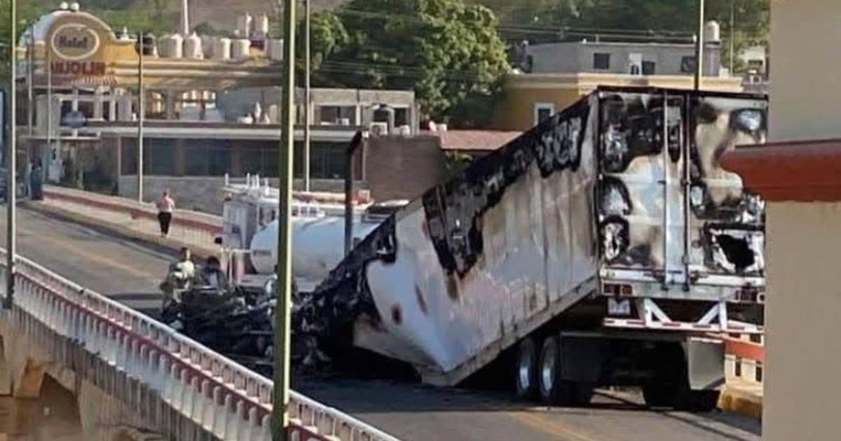 Camión incendiado en bloqueo de San Ignacio, Sinaloa, con bomberos en la escena.