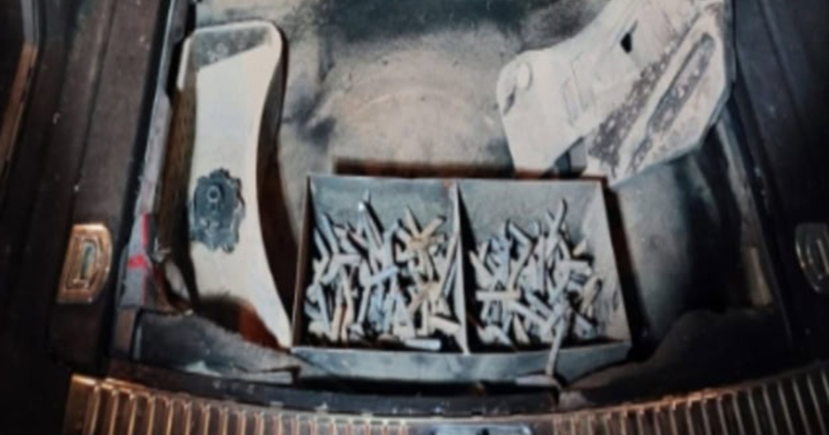 Maletero de vehículo acorazado con cajas de tornillos y sistema de sujeción polvoriento.