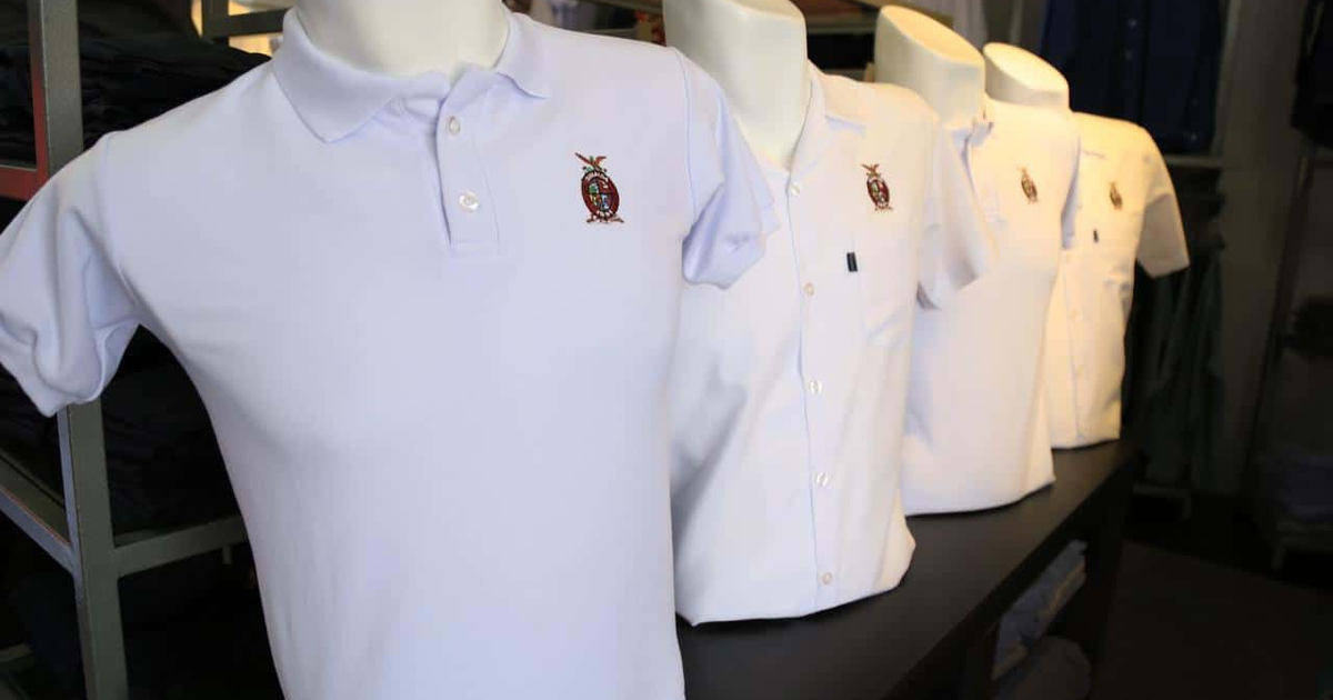 Camisetas polo blancas con logotipo en maniquíes de tienda, relacionadas con el canje de uniformes escolares en Sinaloa.