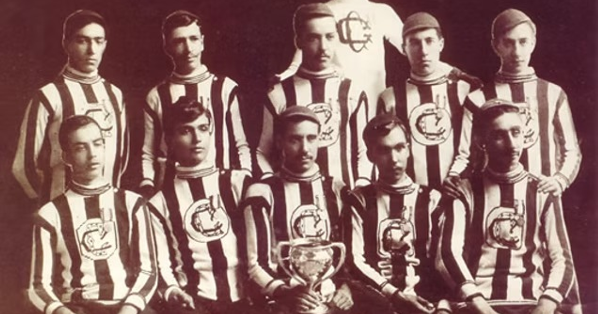 Equipo de fútbol histórico con camisetas a rayas y copa, principios del siglo XX.