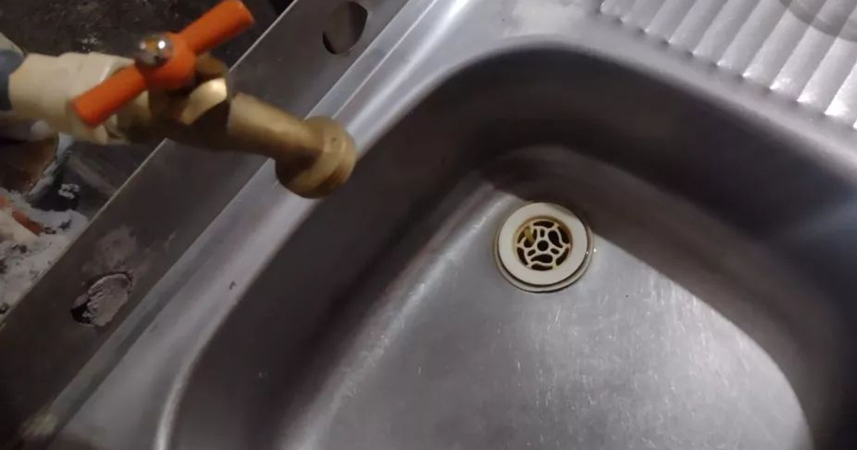 Grifo de metal con manija naranja sobre fregadero de acero inoxidable, vinculado a la interrupción de agua en Mazatlán.