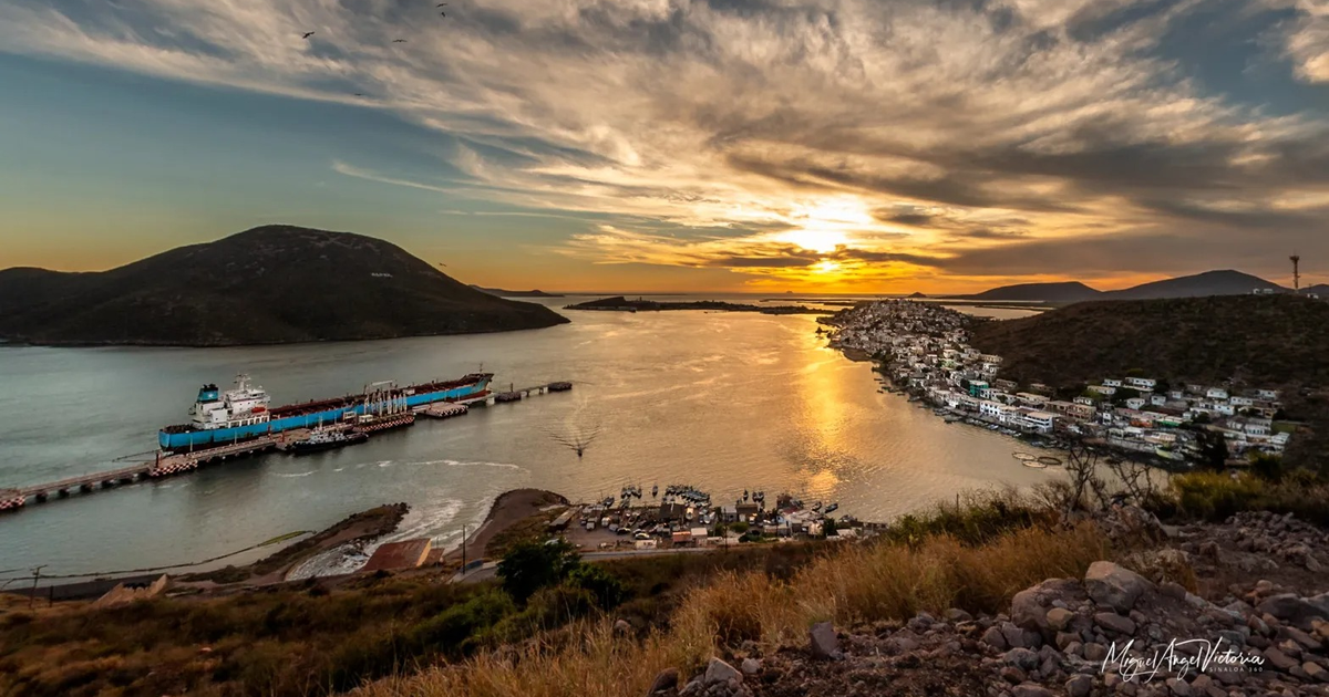 Paisaje marino al atardecer con barco en muelle y montañas al fondo en Topolobampo