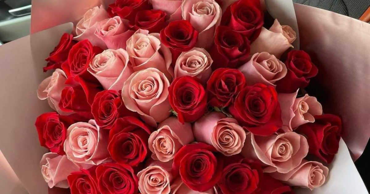 Ramo de rosas multicolor con rosas rojas y rosas de color rosa claro en un envoltorio elegante.