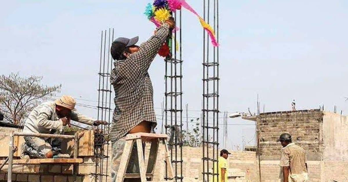 Trabajadores decorando una estructura en un sitio de construcción durante el Día de la Santa Cruz.