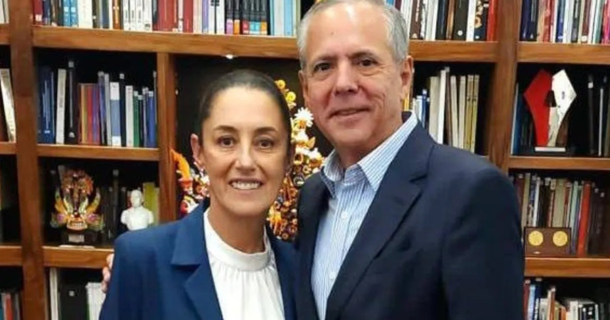 Dos personas posan formalmente frente a una estantería de libros, reflejando un ambiente de discusión seria.