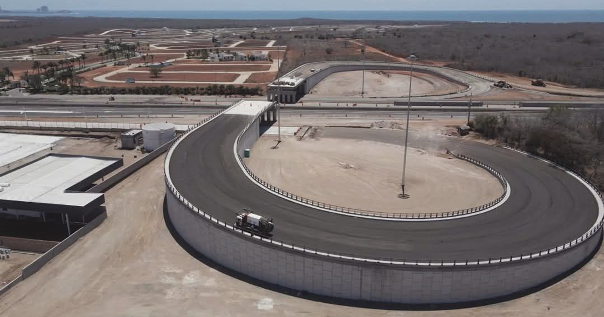 Vista aérea de un circuito de carreras con áreas de construcción y un camión en la pista, en un paisaje semiárido.