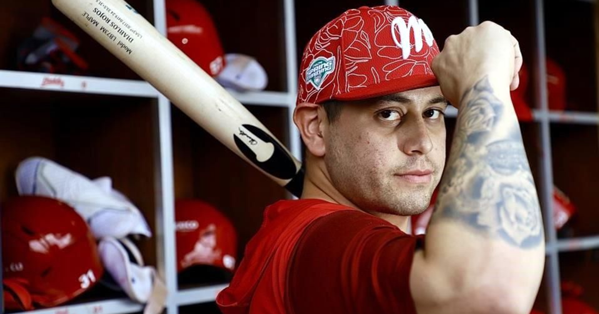Jugador de béisbol de Diablos Rojos del México con bate en vestuario