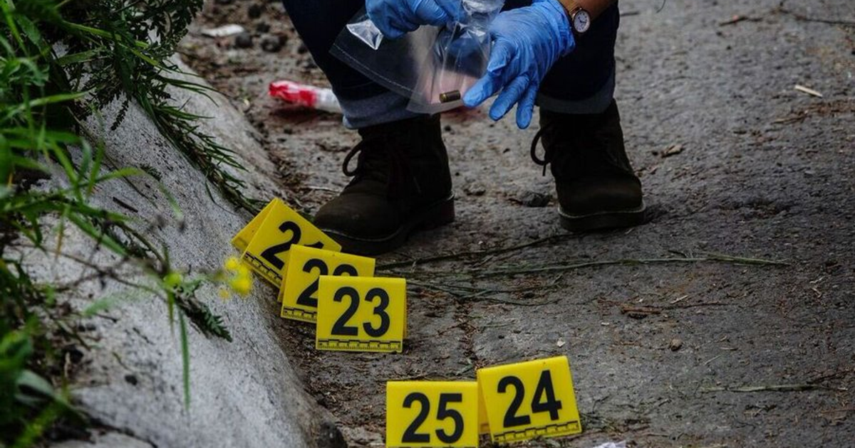 Investigador forense en escena de crimen en El Tablero, Oaxaca, con señales de evidencia en el suelo.