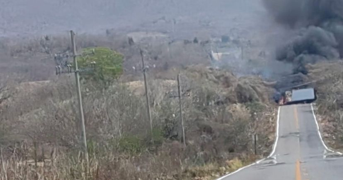 Camión volcado en carretera rural con humo negro, relacionado con enfrentamiento armado en Siqueros.