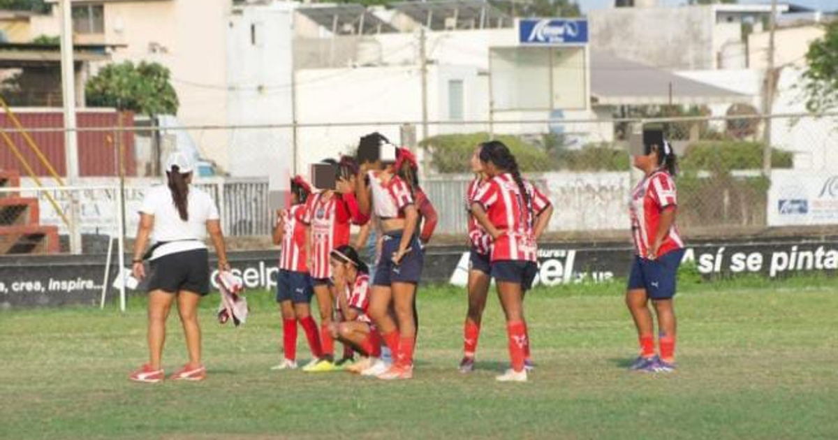 Jugadoras de fútbol en campo de césped con entrenadora, durante torneo femenil infantil en día soleado.