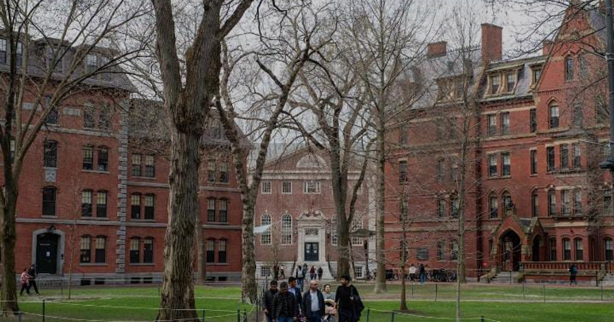 Campus de Harvard con edificios de ladrillo rojo y personas caminando en un día nublado.