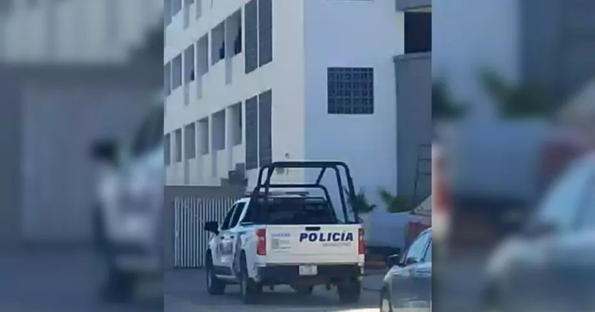 Camioneta de policía estacionada frente a un edificio en Mazatlán, relacionada con un caso de hallazgo de cadáver.