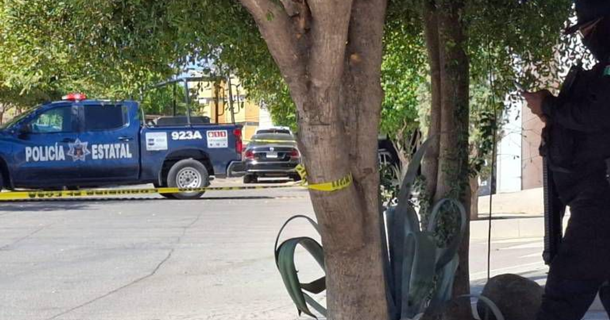 Vehículo policial en escena del crimen en Culiacán, con cinta amarilla y oficial presente.