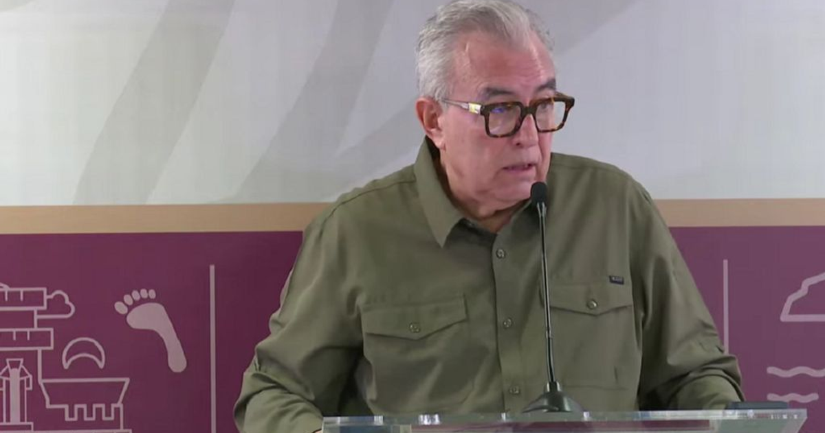 Hombre con gafas hablando en un podio de cristal durante una conferencia sobre el IMSS-Bienestar.