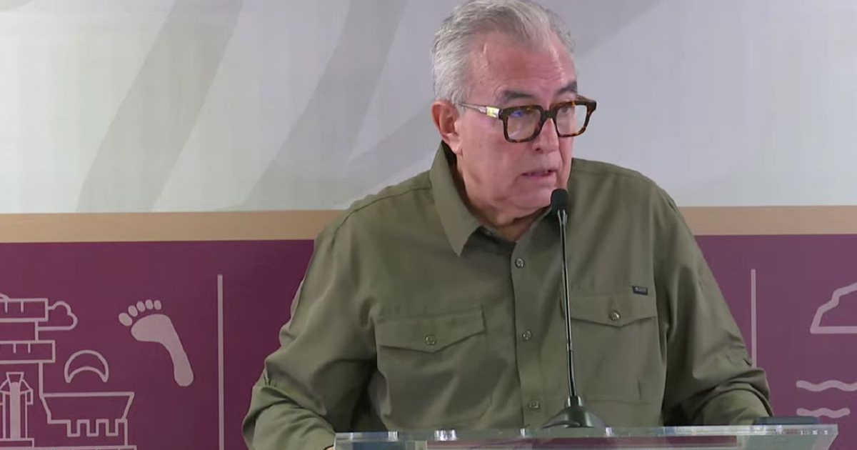 Hombre hablando en conferencia sobre transparencia en salud, con fondo cultural.