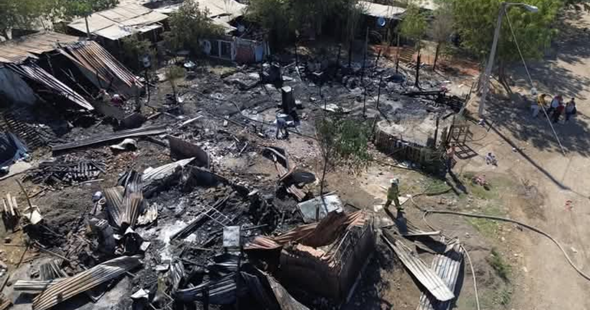 Escombros y estructuras quemadas tras incendio en Jaripillo, con personas trabajando en la limpieza.