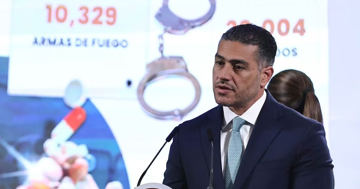 Hombre hablando en conferencia con gráficos de armas y esposas de fondo