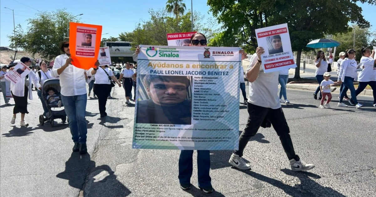 Manifestantes en Culiacán con carteles, uno busca a Paul Leonel Jacobo Benitez, en protesta por desapariciones forzadas.