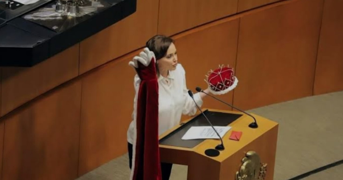 Senadora en podio con capa y corona durante debate parlamentario sobre elección de jueces.