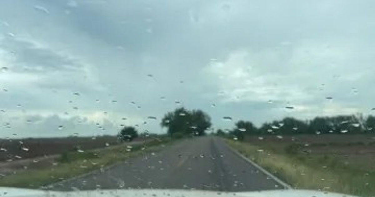 Carretera en Sinaloa vista desde un vehículo con gotas de lluvia en el cristal y cielo nublado.