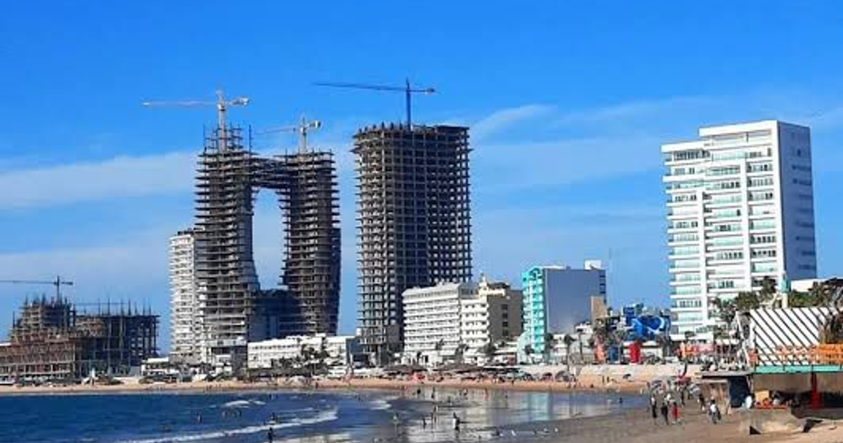 Playa de Mazatlán con edificios en construcción y grúas, reflejando el impacto de la inseguridad en el desarrollo turístico.