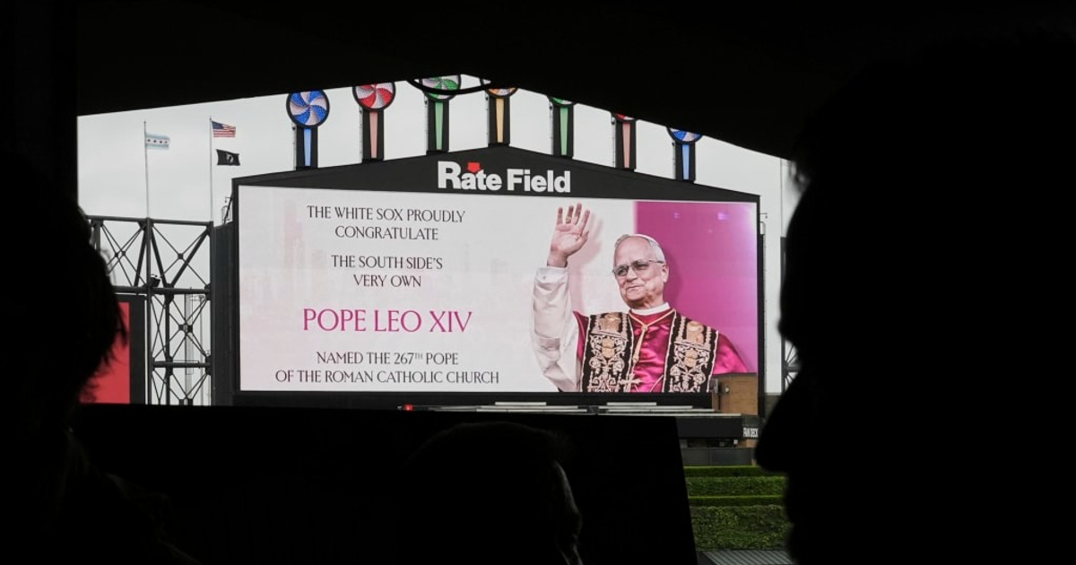 Pantalla en el estadio Guaranteed Rate Field felicitando al Papa Leo XIV, con la estructura del estadio y banderas al fondo.