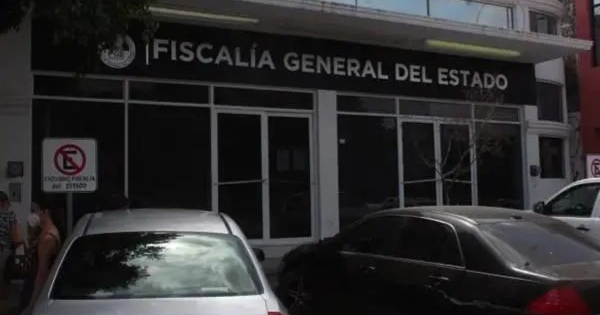 Edificio de la Fiscalía General del Estado con autos y personas en el entorno urbano.