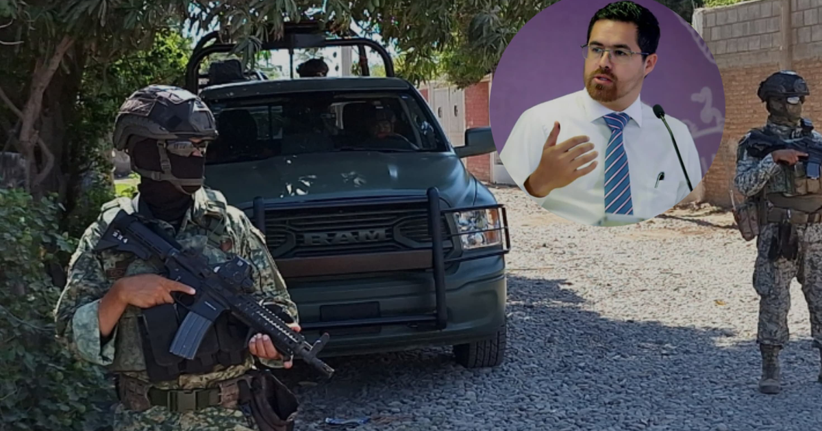 Dos soldados en uniforme militar con un vehículo de fondo y una persona hablando en un evento.